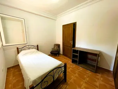 a small bedroom with a bed and a fireplace at Appartement de plain-pied, piscine et mer in Bouznika