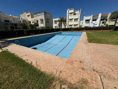 a swimming pool in front of a large building at Triplex à 5 min de la plage ! in Temara