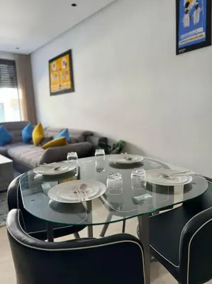 a glass table in a living room with plates and glasses at Cozy princesse living maarif in Casablanca