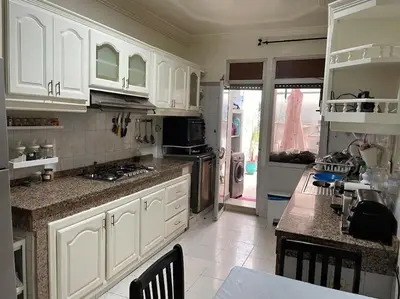 a kitchen with white cabinets and a table with chairs at La Belle Vue Cosy Apartment in Casablanca