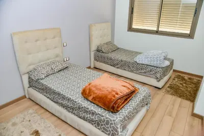 a room with two beds and a chair at Le Joyau du Parc in Mohammedia