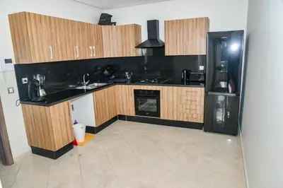 a kitchen with wooden cabinets and a black refrigerator at Le Joyau du Parc in Mohammedia