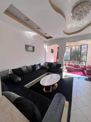 a living room with a black couch and a table at MOHAMMEDIA Rico Flores in Mohammedia