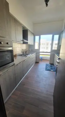 a large kitchen with wooden floors and stainless steel appliances at Cité Marine in Mansouria