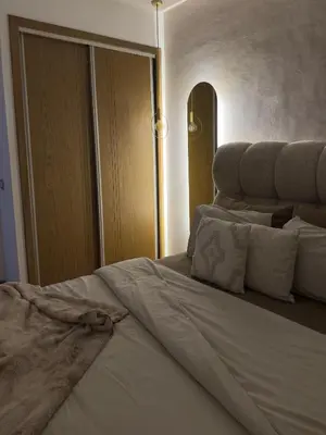 a bedroom with a bed with white sheets and pillows at Beau studio au cœur du parc in Mohammedia