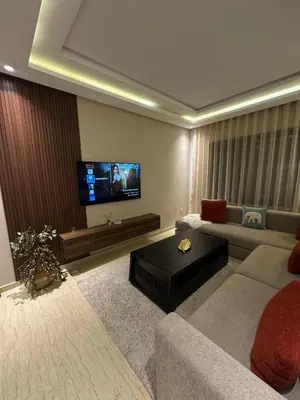 a living room with a couch and a flat screen tv at Beau studio au cœur du parc in Mohammedia
