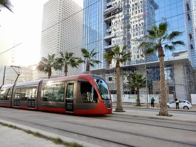 a red tram driving down a street with palm trees at Zen & Welcoming CFC - Garage & Tramway in Casablanca