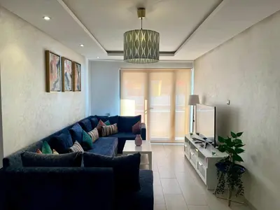 a living room with a blue couch and a tv at Zen & Welcoming CFC - Garage & Tramway in Casablanca