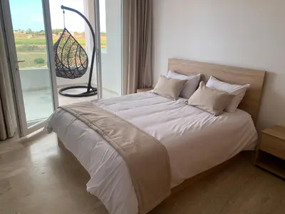 a bedroom with a large bed with a large window at Appartement de luxe avec vue sur mer in Bouznika