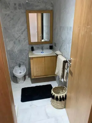 a bathroom with a sink and a toilet and a mirror at Appartement de luxe avec vue sur mer in Bouznika