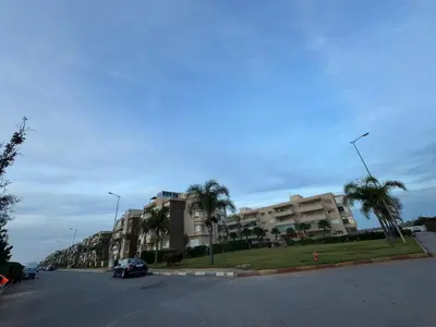 a street with a parking lot with palm trees and a building at Appartement de luxe avec vue sur mer in Bouznika