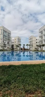 a large swimming pool in front of some buildings at Grand appartement vue golf a 2 min de la plage Bouznika in Bouznika