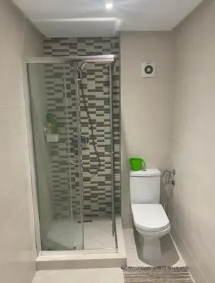 a bathroom with a toilet and a glass shower at Grand appartement vue golf a 2 min de la plage Bouznika in Bouznika