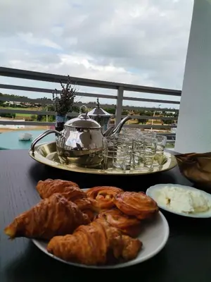 two plates of pastries and a tea kettle on a table at Grand appartement vue golf a 2 min de la plage Bouznika in Bouznika