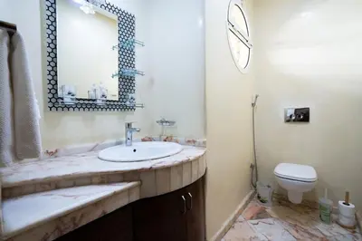 a bathroom with a sink and a toilet and a mirror at Maison avec Piscine Proche Plage in El Harhoura