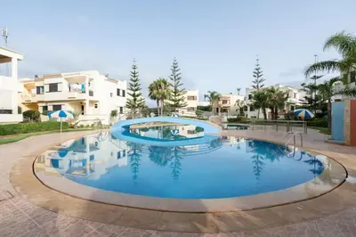 a large swimming pool with blue water at Maison avec Piscine Proche Plage in El Harhoura
