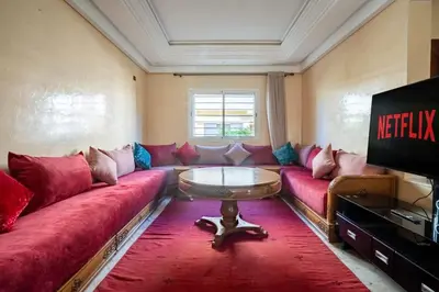 a living room with a red couch and a table at Maison avec Piscine Proche Plage in El Harhoura