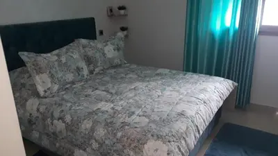 a bed with a comforter and pillows in a bedroom at Appartement Sidi Rahal in Berrechid