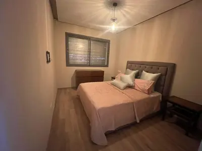 a bedroom with a bed with pink pillows and a window at Cozy New Apartment in Tamaris in Dar Bouazza