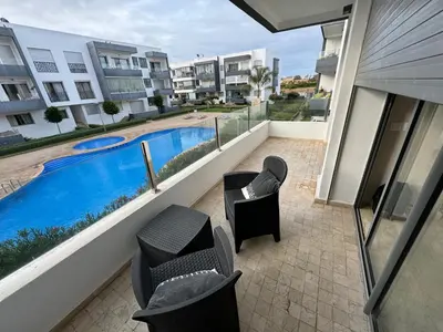a balcony with two chairs and a swimming pool at Cozy New Apartment in Tamaris in Dar Bouazza