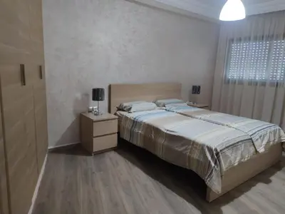a bedroom with a bed and a dresser and a window at Appartement de standing in Casablanca