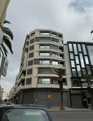 a car parked in front of a tall building at Studio meublé neuf Maarif au centre de Casablanca 3 minutes de stade Mohamed V in Casablanca