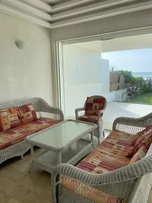 a living room with wicker chairs and a glass table at Villa pied dans l'eau skhirat in Skhirat