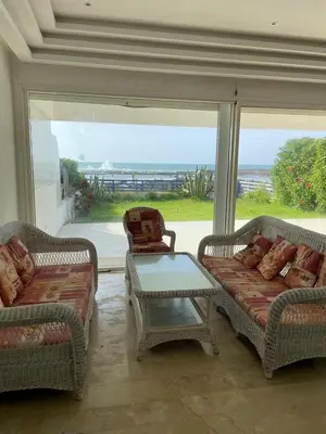 a living room with two couches and a table and a window at Villa pied dans l'eau skhirat in Skhirat