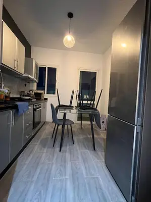 a kitchen with a table and chairs and a refrigerator at Appartement de Luxe à Bahia Golf Beach Spacieux de 126 m in Bouznika