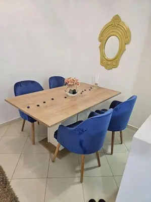 a dining room table with blue chairs and a mirror at Appartement charmant à 5 min de la plage in Skhirat