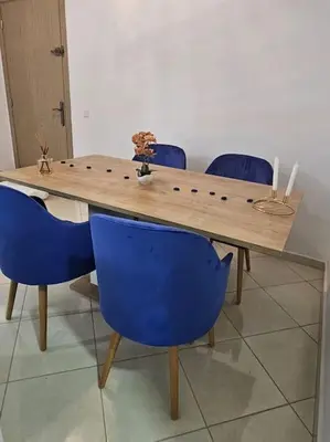 a wooden table with four blue chairs around it at Appartement charmant à 5 min de la plage in Skhirat