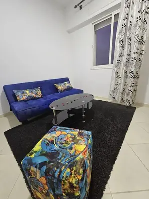 a living room with a blue couch and a table at Appartement charmant à 5 min de la plage in Skhirat