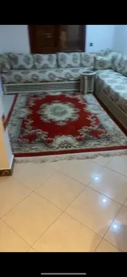a living room with a red rug and a couch at Charmant appartement in Casablanca