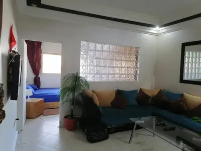 a living room with a blue couch and a bed at Studio Avenue de France in Rabat