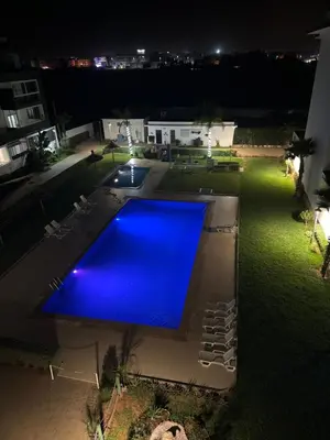 a large blue swimming pool at night at Rayyan Appartement in Bouznika