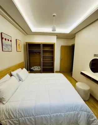 a bedroom with a large white bed and a tv at Appartement a zenata ain-harrouda casablanca in Mohammedia