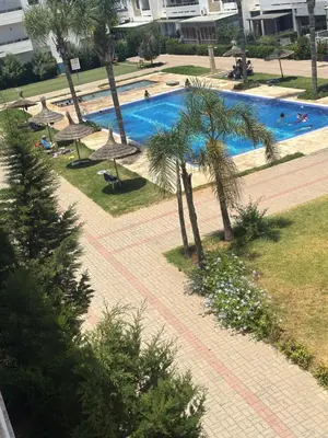 a swimming pool with palm trees and umbrellas at Marbella beach el mansouria in Mansouria
