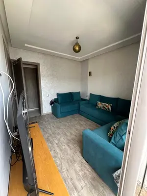 a living room with a blue couch and a tv at Marbella beach el mansouria in Mansouria
