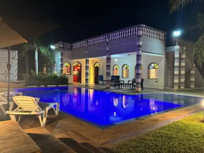 a swimming pool in front of a house at night at Villa Ines avec piscine privée in Sidi Moussa Ben Ali