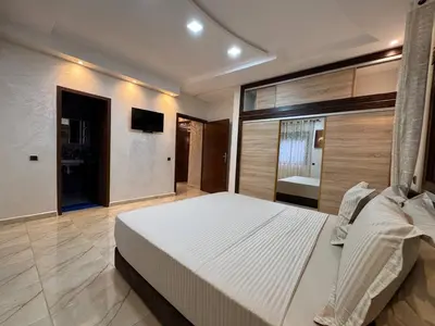 a bedroom with a large white bed and a bathroom at Villa Ines avec piscine privée in Sidi Moussa Ben Ali