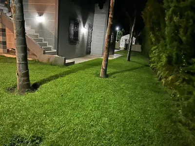 a green lawn with palm trees in front of a building at Villa Ines avec piscine privée in Sidi Moussa Ben Ali