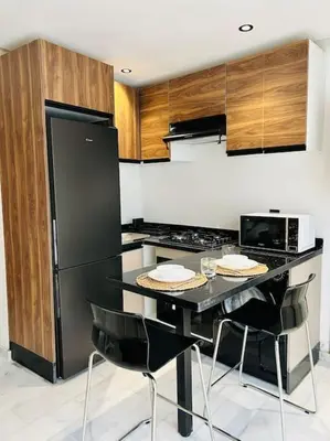 a kitchen with a black refrigerator and a table with chairs at Oasis 9 Cozy studio in Downtown Maarif in Casablanca