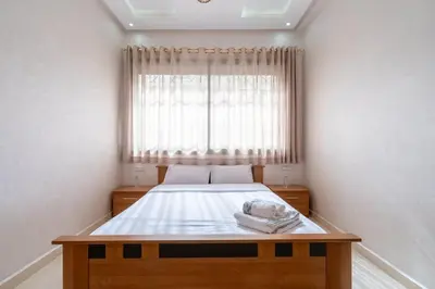 a small bedroom with a bed with a window at Appartement Proche Plage in Bouznika