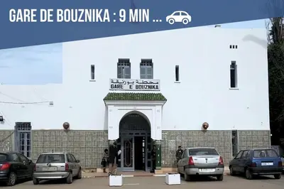 a building with cars parked in a parking lot at Appartement Proche Plage in Bouznika
