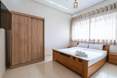 a bedroom with a bed and a large window at Appartement Proche Plage in Bouznika