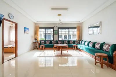 a living room with a green couch and a table at Appartement Proche Plage in Bouznika