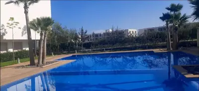 a blue swimming pool with palm trees and a building at blue beach in Sidi Rahal