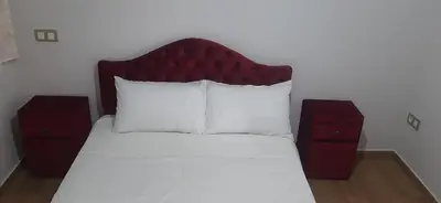 a bed with a red headboard and two night stands at blue beach in Sidi Rahal