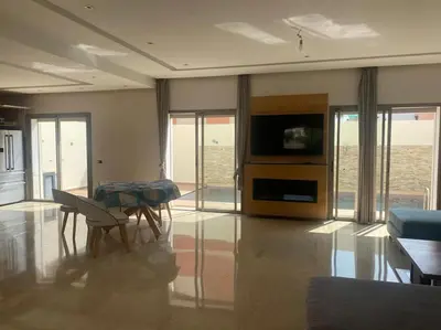 a living room with a table and a television at Villa avec piscine Mohammedia in Mohammedia