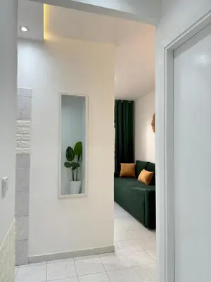 a living room with a green couch and a mirror at SUITOUISS - Agdal - Studio en plein cœur de Rabat à 5 minutes du grand mall Arribat Center - centre ville in Rabat